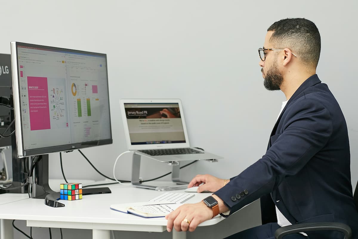 Profissional homem em escritório com computador e notebook para automação de processos.