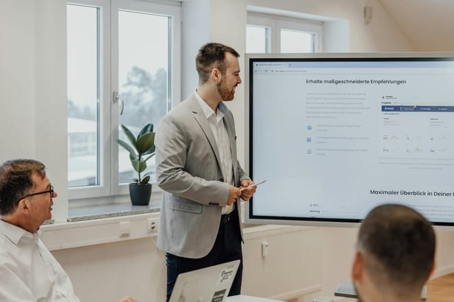 Profissionais homens em uma sala de reunião com uma tela com apresentação fazendo gestão de leads.
