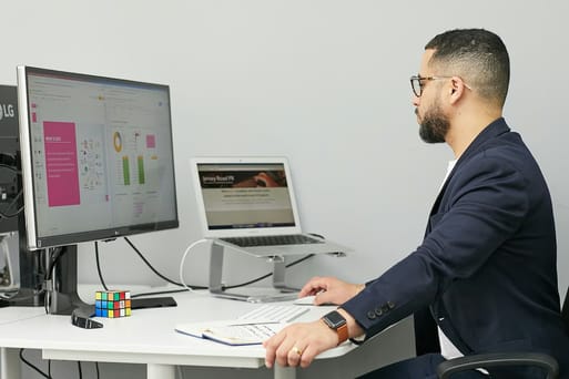 Profissional homem em escritório com computador e notebook para automação de processos.